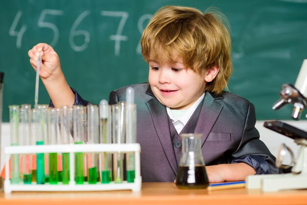 Petit enfant apprenant la chimie dans le laboratoire de l'école. Petit garçon au cabinet chimique. enfant en blouse de laboratoire apprenant le laboratoire de chimie chimique. Retour à l'école. expérimenter avec des produits chimiques. Scientifique au travail.