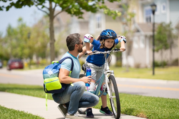 Petit enfant apprenant à faire du vélo avec son père dans le parc, père enseignant à son fils le cyclisme père et fils l