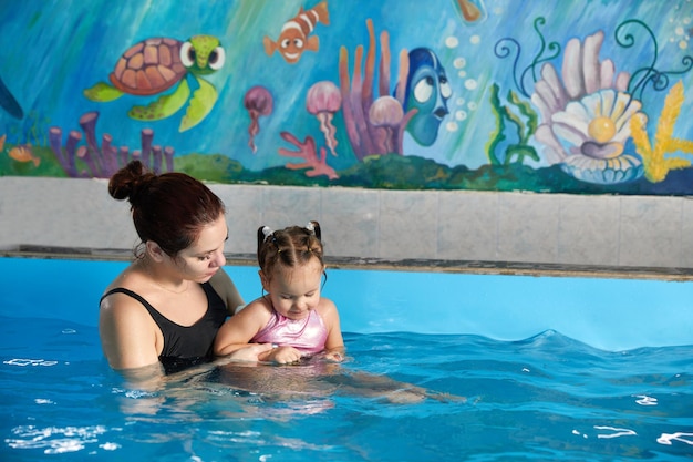 Petit enfant apprenant à nager dans la piscine avec un professeur