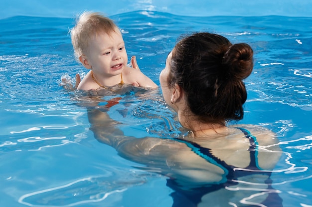 Petit enfant apprenant à nager dans la piscine avec son professeur