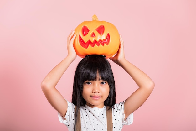 Petit enfant asiatique de 10 ans tenant une citrouille d'Halloween sculptée