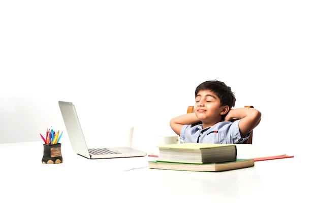 Petit enfant asiatique indien fatigué par les études, donc s'étirant ou faisant la sieste à la table d'étude à la maison