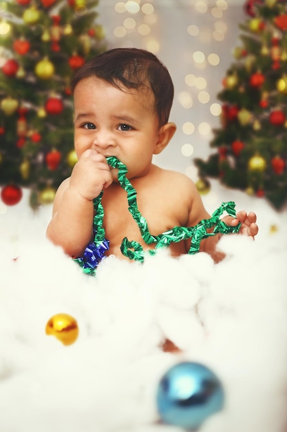 Un petit enfant assis en coton et jouant avec des rubans décoratifs