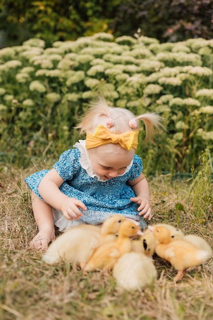 Petit enfant assis dans l'herbe à côté des canetons