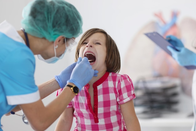 Petit enfant bouche ouverte pour vérifier le rendez-vous du pédiatre mal à la gorge vérifier avec l'outil