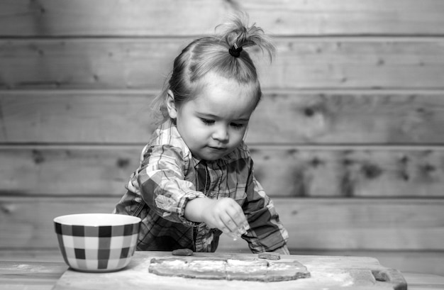 Petit enfant boulanger à la cuisine bébé garçon dans la cuisine aidant à cuisiner jouant avec de la farine