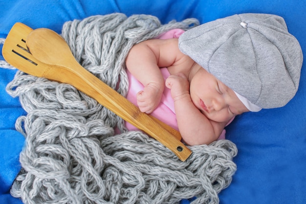 Un petit enfant à la casquette grise repose avec une cuillère