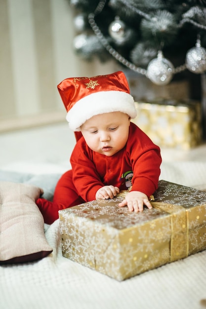 Un petit enfant en costume rouge est assis sur le sol