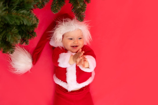 Un petit enfant dans un costume de Père Noël avec arbre de Noël