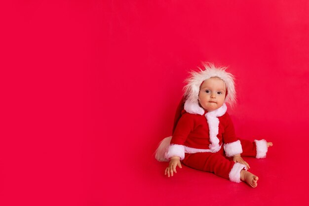 Petit enfant dans un costume de Père Noël est assis oisolated