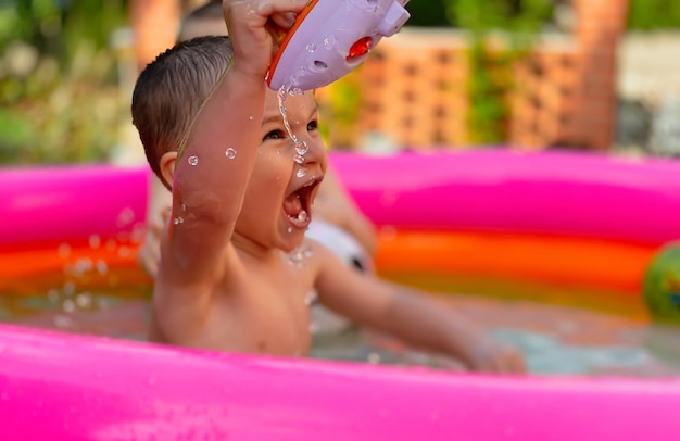 Un petit enfant dans une piscine ronde gonflable pour enfants par temps ensoleillé d'été. Concept d'été et de vacances.