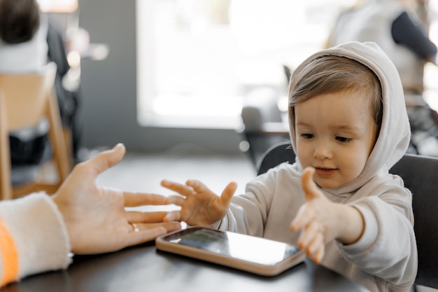 Un petit enfant a une dépendance aux gadgets joue aux gadgets tout le temps regarde des vidéos sur un smartphone