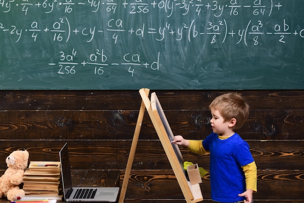 Photo petit enfant écrit au tableau. kid en face de bord avec équation mathématique. élève intelligent étudiant les mathématiques