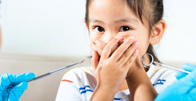 Petit enfant effrayé et ferme la bouche avec les mains Le médecin examine la cavité buccale