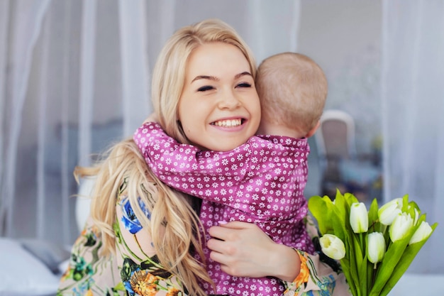 Un petit enfant embrasse maman et donne des fleurs. Le concept d&#39;enfance, d&#39;éducation, de famille