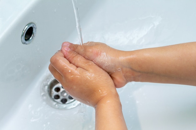 Petit enfant, l'enfant se lave les mains sous le robinet de l'évier