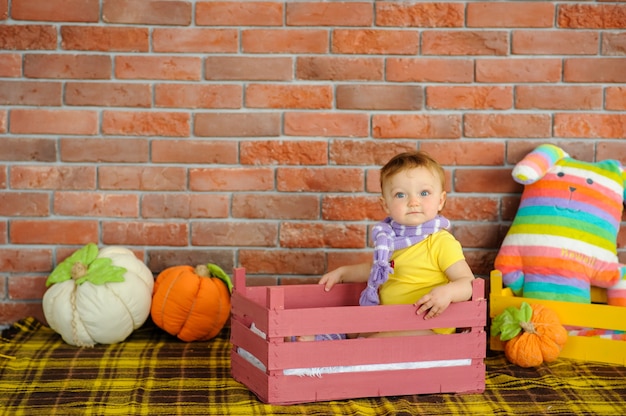 Un petit enfant est assis dans une boîte en bois.