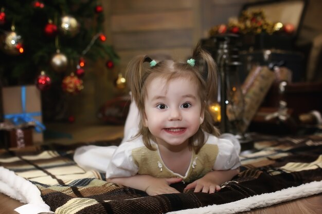 Un petit enfant est assis avec un sapin avec des décorations de Noël