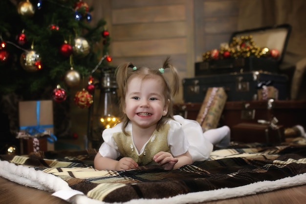 Un petit enfant est assis avec un sapin avec des décorations de Noël