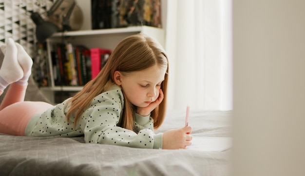 Petit enfant fille dessiner ou écrire à la main dans un journal au crayon Enfant apprenant et faisant ses devoirs