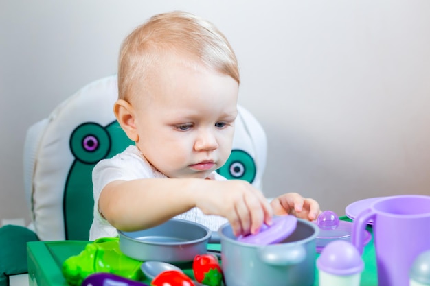 Petit enfant flou tenant un légume jouet dans ses mains sur le fond des plats