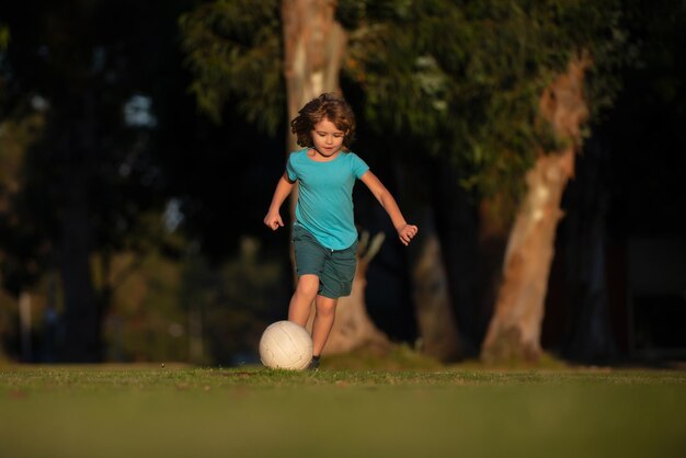 Petit enfant garçon jouant au football sur le terrain avec ballon de football Concept de sport pour enfants Enfant joueur de football dans le parc