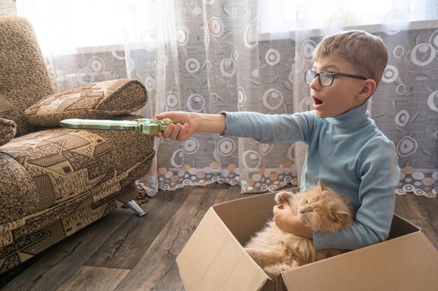 Un petit enfant un garçon joue à un pirate avec un chat assis dans une boîte jeux d'enfants dans le