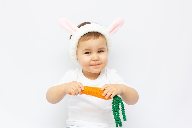 Un petit enfant habillé en lapin avec une carotte