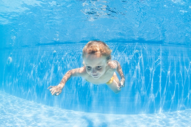 Petit enfant heureux plonger sous l'eau dans la piscine