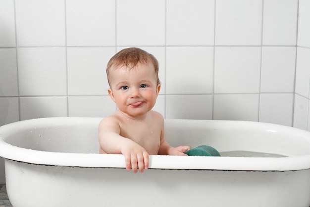 Photo petit enfant heureux se baigne dans une baignoire