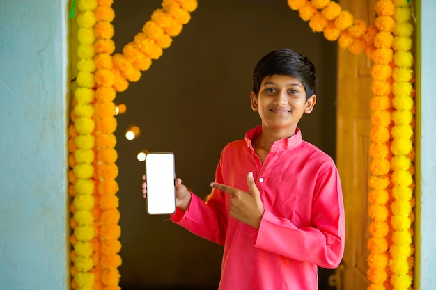 Petit enfant indien en tenue traditionnelle et montrant un smartphone