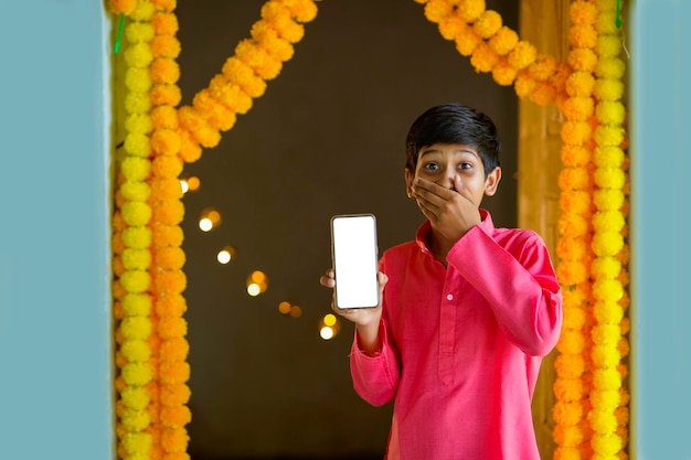 Petit enfant indien en tenue traditionnelle et montrant un smartphone