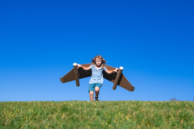 Petit enfant joue l'astronaute ou l'enfant pilote sur le fond du ciel bleu les enfants avec des ailes en papier jetp