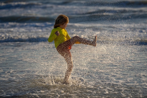 Petit enfant jouer dans l'eau et faire des éclaboussures enfant s'amuser avec des gouttes d'été enfant jouer dans les vagues mer ki