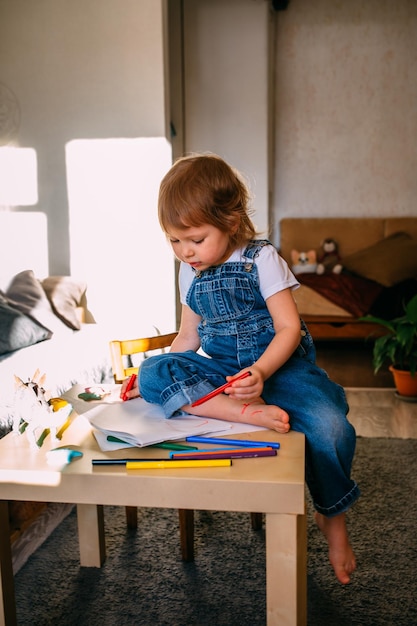 Petit enfant à la maison à la table des enfants dessine avec des feutres