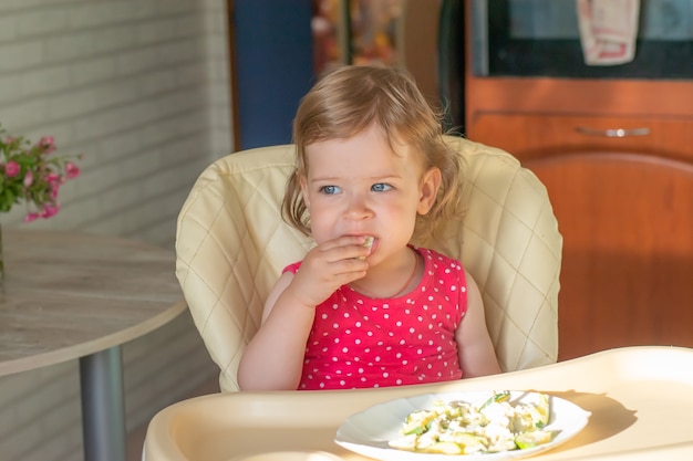 Un petit enfant mange des lasagnes appétissantes avec des légumes