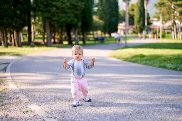 Petit enfant marchant le long du chemin dans le parc verdoyant