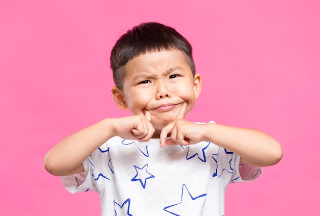 Un petit enfant met un doigt sur la joue