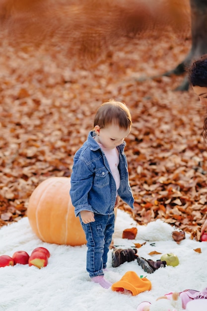 Petit enfant mignon dans le parc sur une feuille jaune avec citrouille en automne