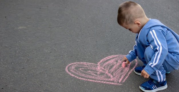 Le petit enfant mignon dessine avec la craie dehors