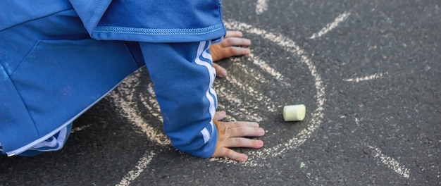 Le petit enfant mignon dessine le soleil avec la craie dehors