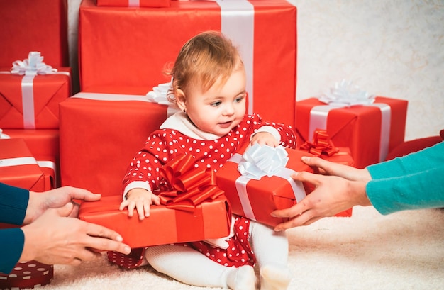 Petit enfant mignon tient une boîte à cadeaux célébrations concept mignons bébés avec une boite à cadeaux rouge sur blanc