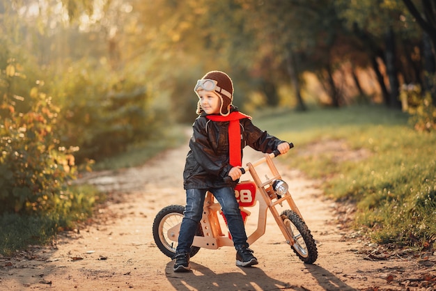 Petit enfant monté sur un vélo d'équilibre en vêtements d'extérieur à l'automne