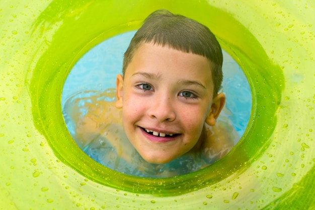 Un petit enfant nage dans la piscine en été en vacances le garçon se réjouit et sourit l'enfant joue dans la piscine