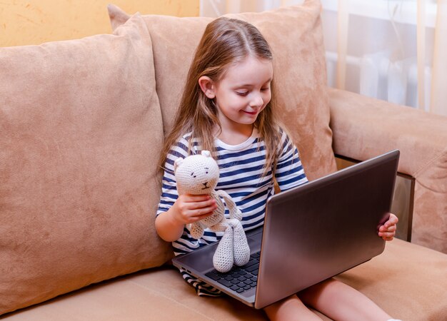 Petit enfant avec netbook et peluche