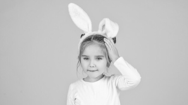 Petit enfant de Pâques dans des oreilles de lapin sur fond jaune