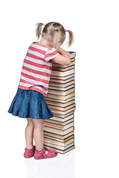 Petit enfant pleure appuyé sur une pile de livres, isolé sur fond blanc