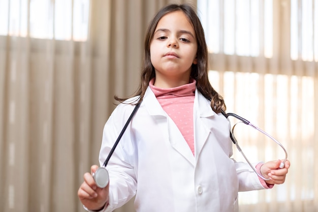 Petit Enfant Posant Drôle Avec L'uniforme Du Médecin Et Un Stéthoscope