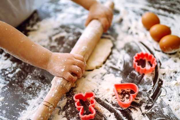 Petit enfant préparant la pâte pour la cuisson. Petites mains pétrissant la pâte et la pâte roulée