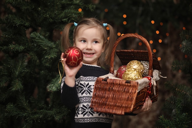 Un petit enfant près de l'arbre du Nouvel An. Les enfants décorent le sapin de Noël. Bébé dans un pull près d'un arbre vert en studio.